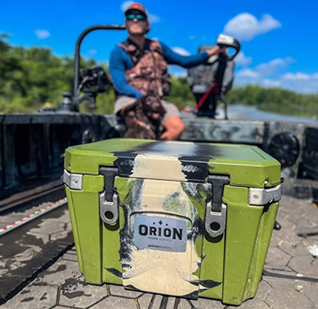 orion cooler on the front deck of a jon boat with smiling motorist behind it
